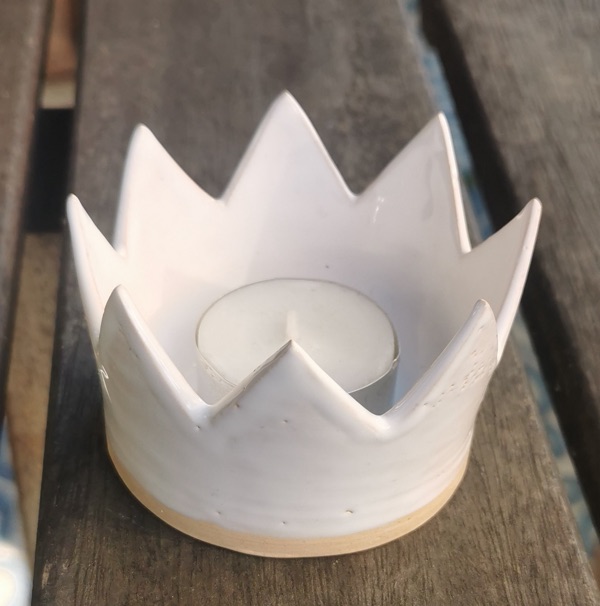 Weißes Windlicht in Kronenform mit Teelicht auf einem Holztisch