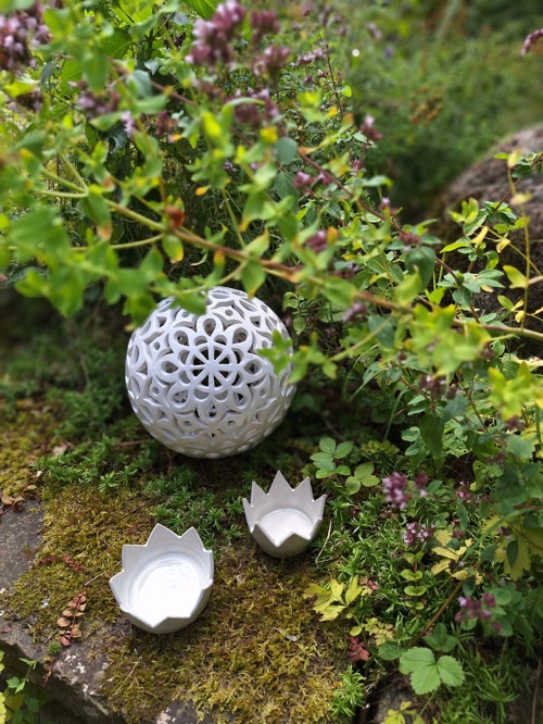 Lichtkugel und zwei kleine weiße Kronen zwischen Pflanzen im Garten