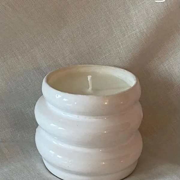 Weißes, gerilltes Keramikgefäß mit Kerze